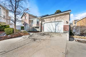 View of front facade featuring concrete driveway, brick siding, an attached garage, and stucco siding