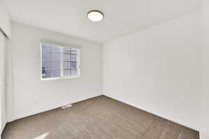 Carpeted empty room with visible vents and baseboards