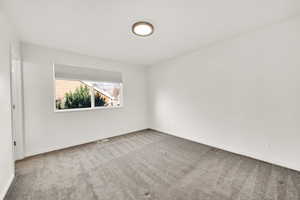Carpeted spare room featuring visible vents and baseboards
