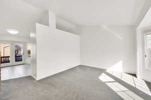 Tiled spare room with lofted ceiling, carpet, and visible vents