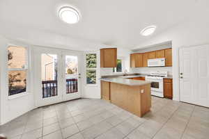 Kitchen featuring light countertops, visible vents, light tile patterned flooring, white appliances, and a peninsula