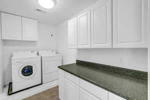 Laundry room with cabinet space, tile patterned flooring, visible vents, and separate washer and dryer