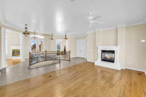 Living area with hardwood / wood-style flooring, decorative columns, visible vents, and a multi sided fireplace