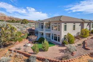 Rear view of house with stucco siding, a patio area, a mountain view, a balcony, and a tiled roof