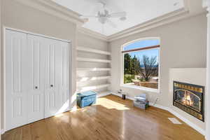 Unfurnished bedroom with baseboards, a glass covered fireplace, wood-type flooring, ceiling fan, and a closet