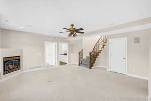 Living room featuring a glass covered fireplace, visible vents, stairway, and baseboards