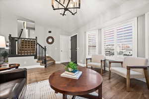 Living area with stairs, baseboards, wood finished floors, and a notable chandelier