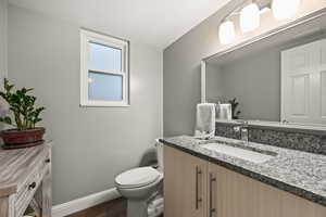 Bathroom with toilet, baseboards, wood finished floors, and vanity