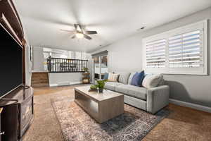 Living room featuring visible vents, ceiling fan, stairway, and baseboards