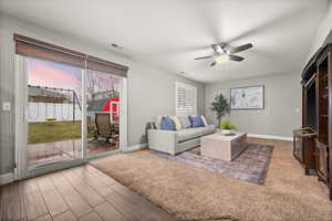 Living room featuring visible vents, ceiling fan, baseboards, and wood finished floors