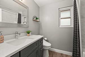 Full bathroom featuring toilet, a shower with shower curtain, wood finished floors, vanity, and baseboards