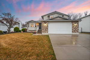 Tri-level home with driveway, a yard, a garage, and brick siding