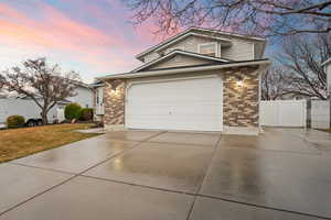 Traditional-style house featuring a gate, brick siding, fence, and concrete driveway