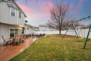 Yard at dusk with a patio area and a fenced backyard