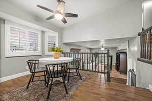 Dining area with lofted ceiling, a ceiling fan, wood finished floors, baseboards, and stairs