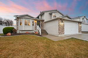 View of front of property with concrete driveway, an attached garage, fence, a front lawn, and brick siding