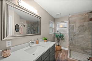 Full bath featuring a stall shower, wood finished floors, vanity, and baseboards