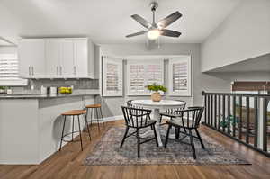 Dining space with ceiling fan, dark wood finished floors, and baseboards