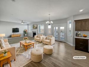 Living area featuring french doors, a notable chandelier, a fireplace, light wood-type flooring, and baseboards