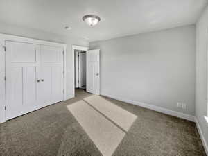 Unfurnished bedroom featuring a closet, carpet, and baseboards