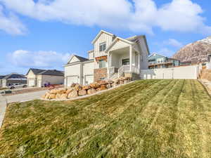 View of front of house with board and batten siding, fence, a mountain view, a residential view, and a front lawn