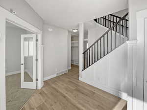 Interior space with visible vents, stairway, baseboards, and wood finished floors