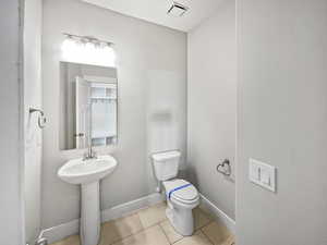 Bathroom featuring toilet, baseboards, visible vents, and tile patterned floors