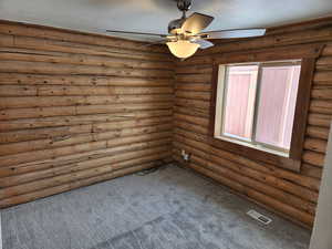 Carpeted empty room with a textured ceiling, ceiling fan, and visible vents