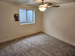 Empty room with carpet flooring, ceiling fan, and baseboards