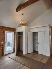 Interior space with vaulted ceiling with beams, wood finished floors, log walls, and baseboards