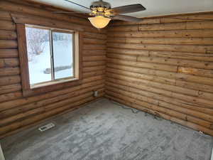 Empty room with carpet floors, ceiling fan, and visible vents