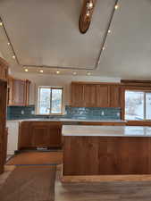 Kitchen featuring light wood-style flooring, a sink, light countertops, brown cabinets, and tasteful backsplash