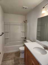 Full bathroom featuring visible vents, bathing tub / shower combination, toilet, a textured ceiling, and vanity