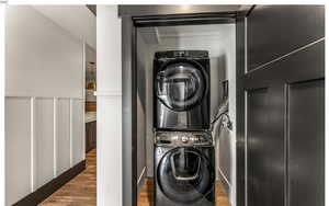 Laundry room featuring laundry area, stacked washing maching and dryer, and wood finished floors