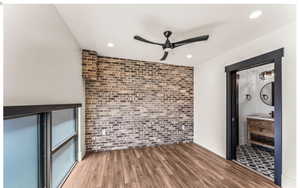 Interior space featuring an accent wall, wood finished floors, brick wall, and recessed lighting