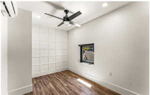 Unfurnished room featuring recessed lighting, a wall unit AC, dark wood finished floors, and baseboards