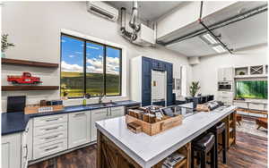 Kitchen with a wall unit AC, dark wood-style floors, a kitchen island, refrigerator, and a sink