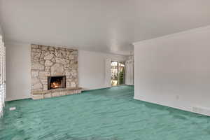 Unfurnished living room featuring baseboards, a stone fireplace, crown molding, and carpet flooring