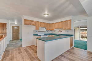 Kitchen with dark countertops, a peninsula, white appliances, new LVP flooring