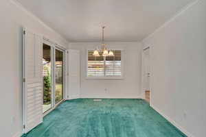 Unfurnished room with baseboards, crown molding, carpet flooring, and an inviting chandelier