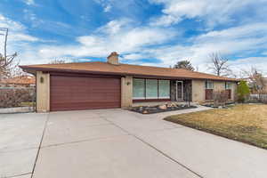 Ranch-style house with a garage, driveway, fence, and a front lawn