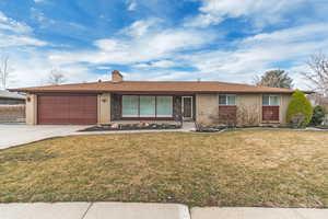 Ranch-style home featuring a garage, a front yard, brick siding, and driveway