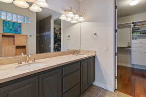 Full bathroom with a walk in closet, a sink, a textured ceiling, and double vanity