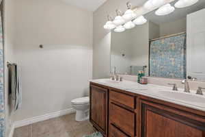 Bathroom featuring double vanity, tile patterned flooring, a sink, and toilet