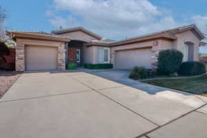 View of front of property with concrete driveway, an attached garage, and stucco siding