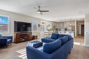 Living room featuring light wood-style floors, baseboards, a ceiling fan, and recessed lighting