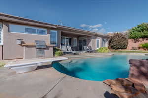 Rear view of property featuring a fenced in pool, a patio, fence, and stucco siding