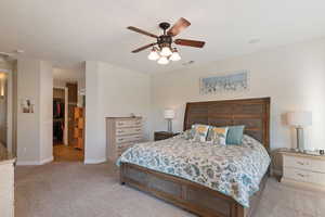 Bedroom with baseboards, ceiling fan, a walk in closet, and light colored carpet