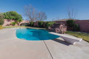 View of pool featuring a fenced in pool, a patio area, a fenced backyard, and a diving board