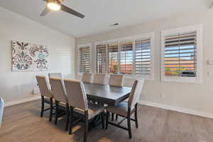 Dining room with lofted ceiling, wood finished floors, visible vents, and baseboards